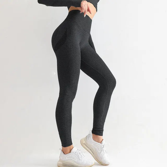 Black high-waisted athletic leggings worn with white sneakers.