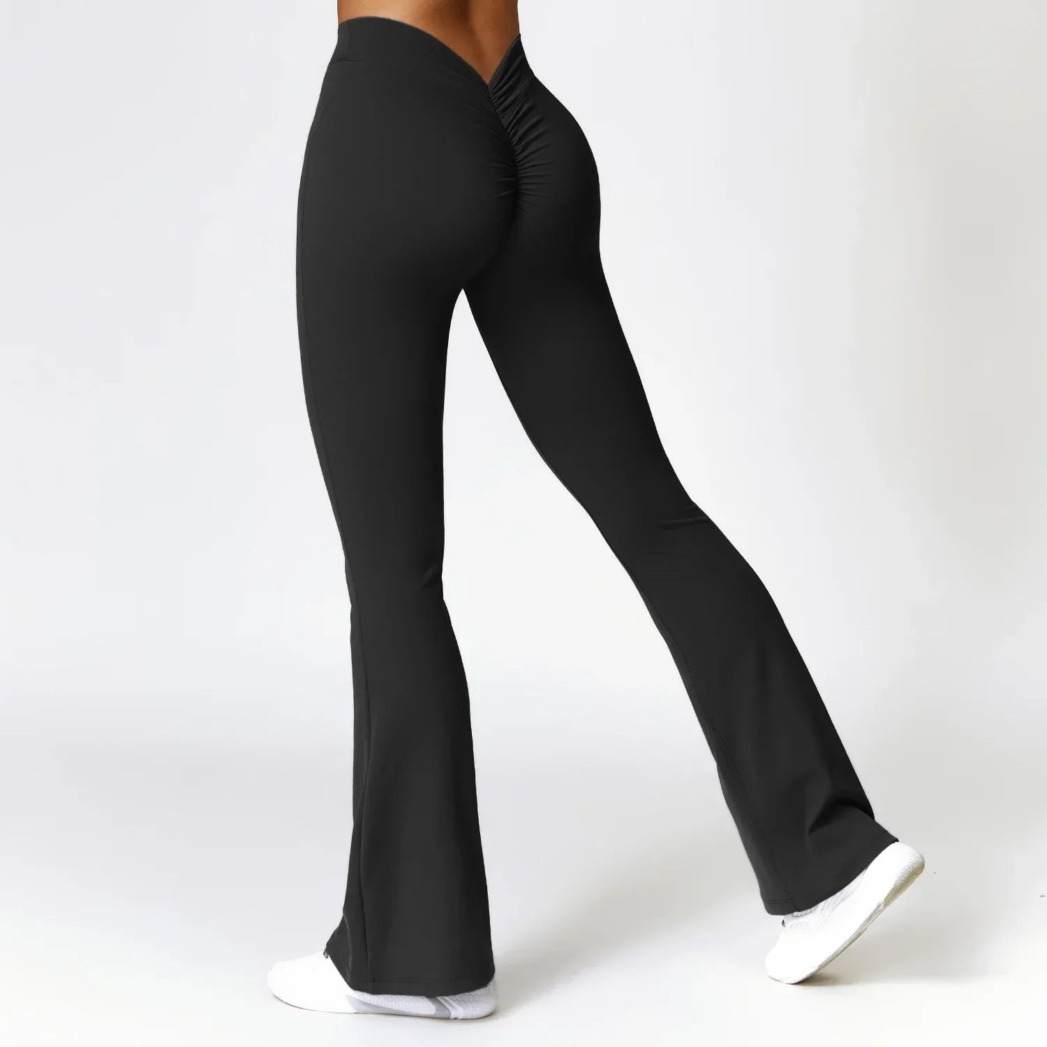 Black flared yoga pants with a ruched waistband and white sneakers.