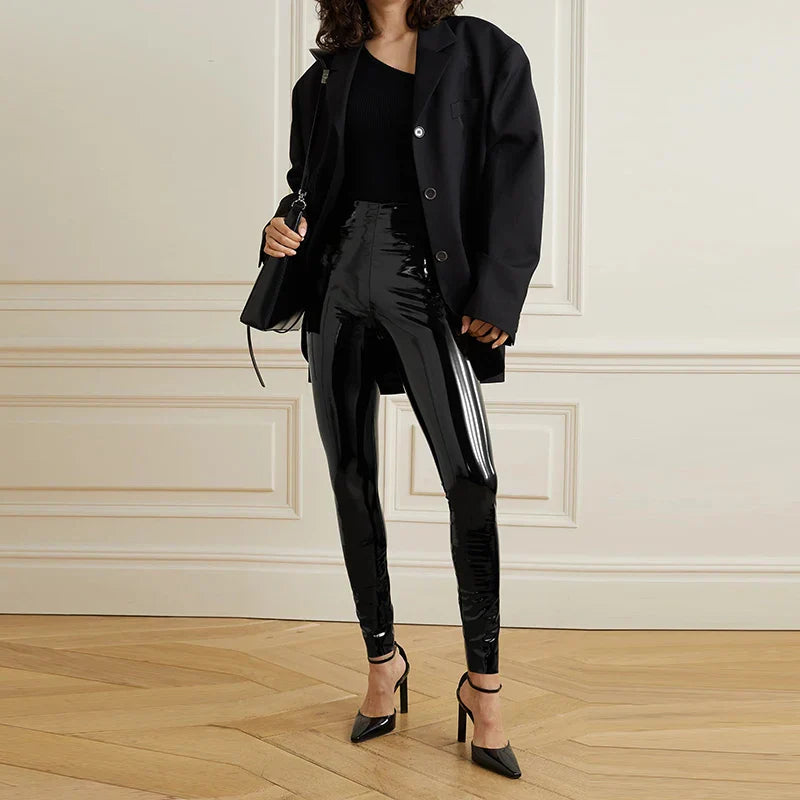 Woman wearing an all-black outfit consisting of an oversized blazer, tight pants, and high heels.