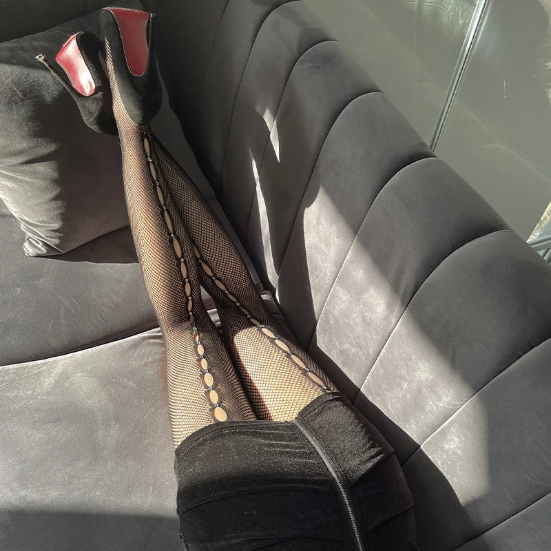 Fishnet stockings with red-accented high heels on a car seat.