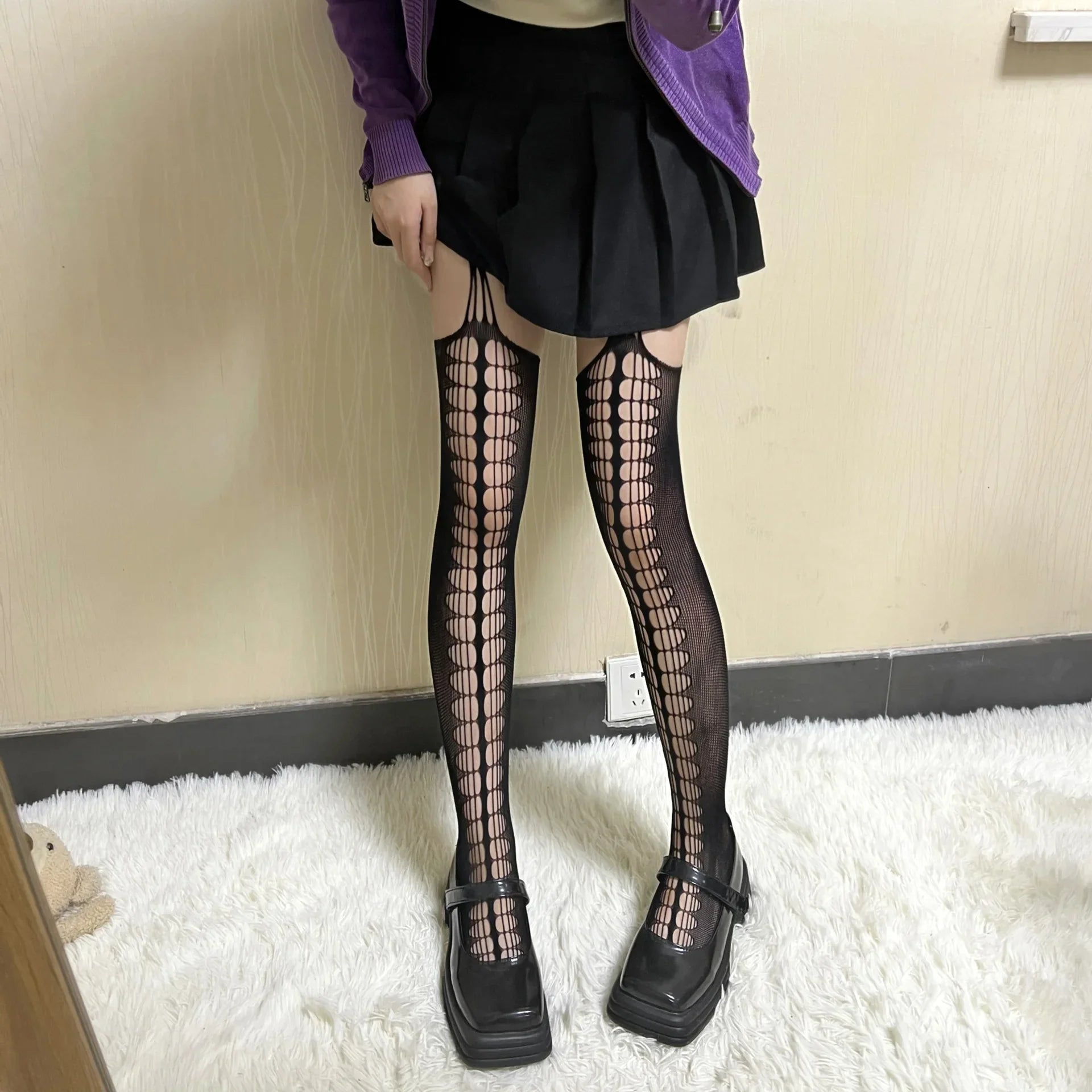 Patterned thigh-high stockings with a vertical lattice design worn with a black skirt and chunky shoes.