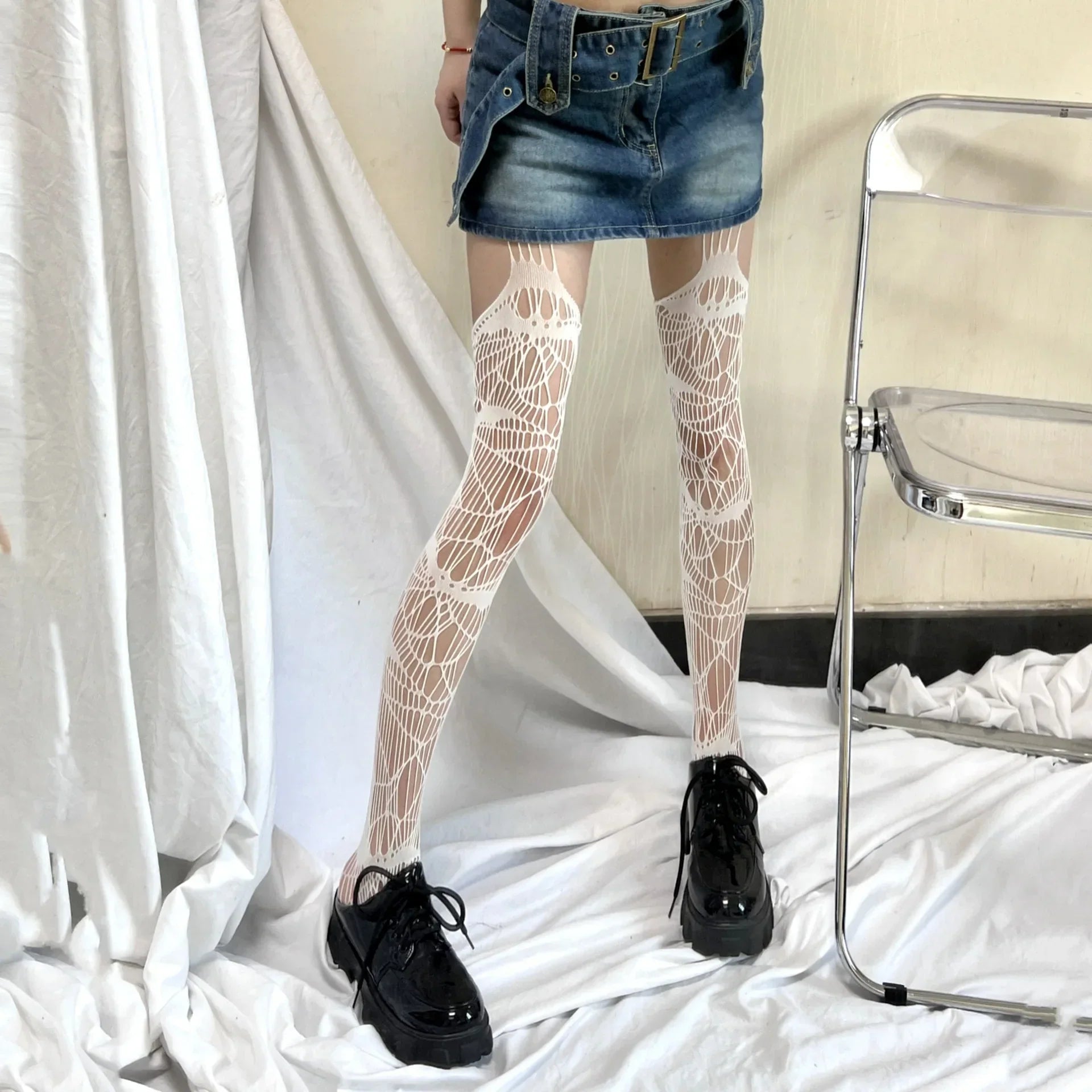 White patterned fishnet stockings worn with a denim miniskirt and black platform shoes.