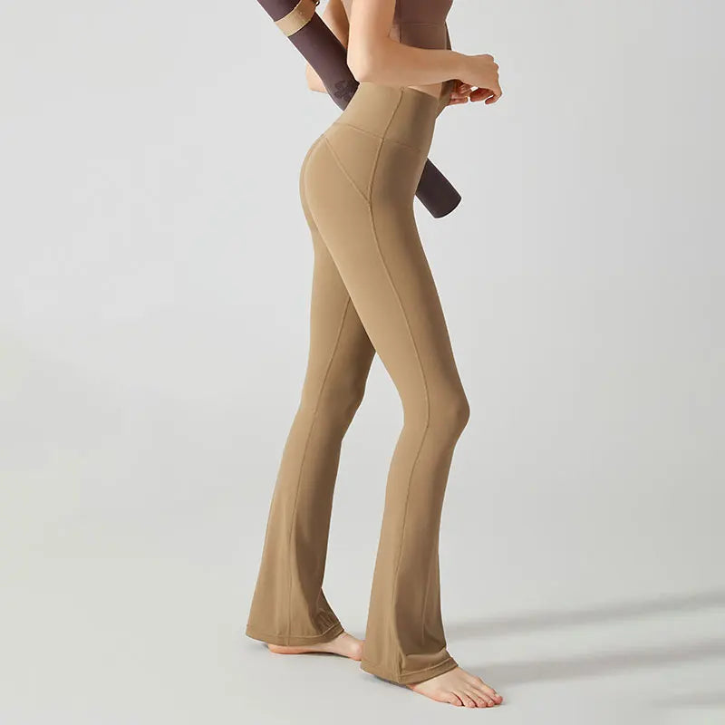 Beige flared yoga pants or leggings worn by a person standing on tiptoes.