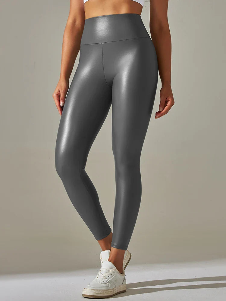 Shiny gray high-waisted leggings worn by a person with white sneakers.