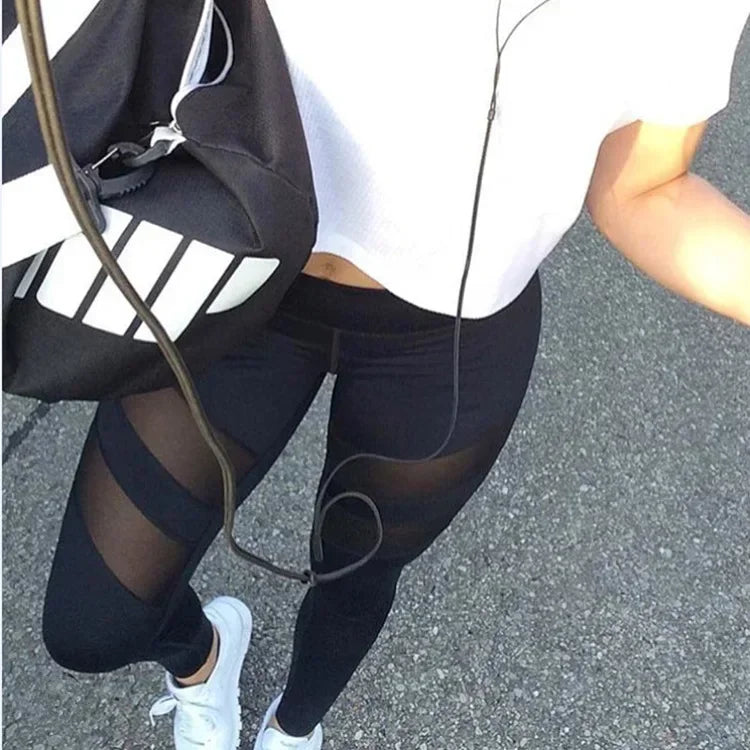 Black athletic leggings with mesh panels worn with white sneakers.