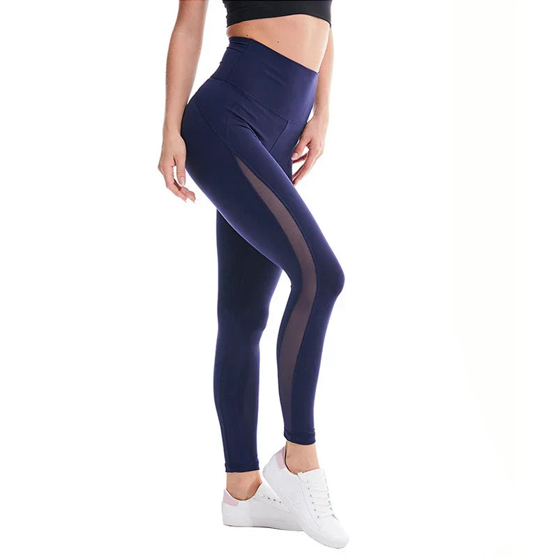 Navy blue high-waisted athletic leggings with mesh side panels and white sneakers.