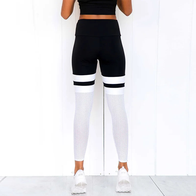 Black and white color-blocked athletic leggings with a mesh pattern on the lower legs.