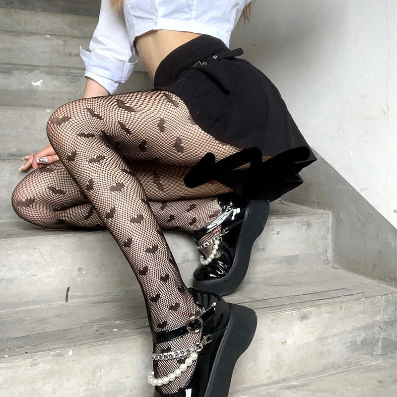 Fishnet stockings with bow patterns worn with a black skirt and platform shoes.