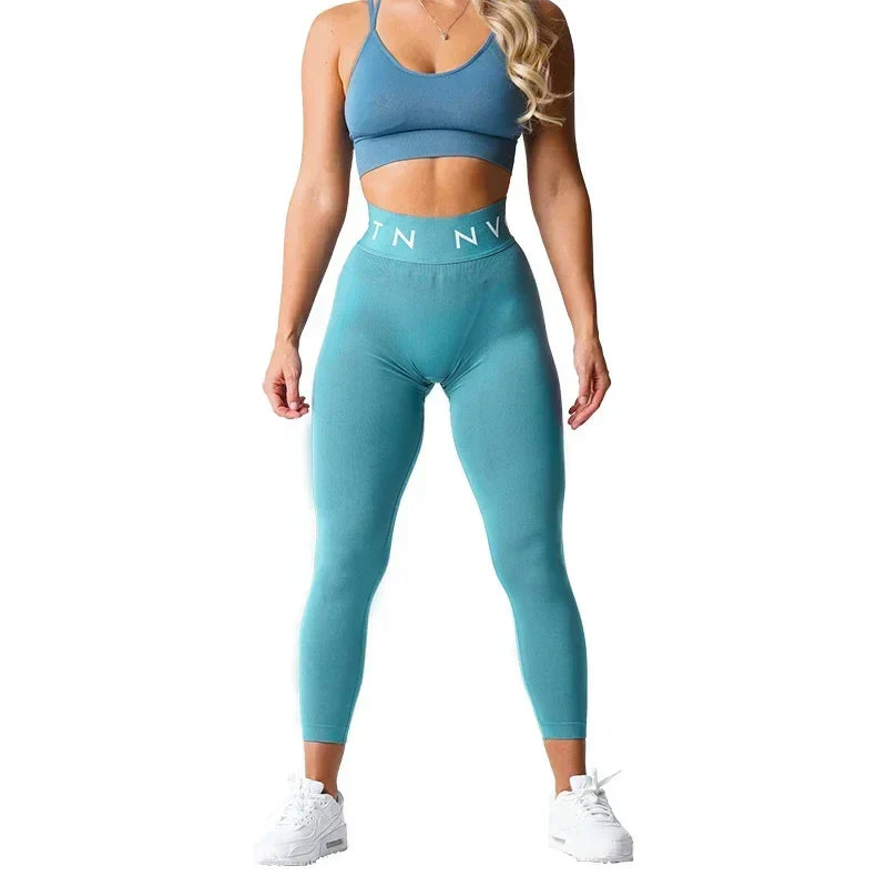 Woman wearing blue workout attire consisting of a sports bra and high-waisted leggings.