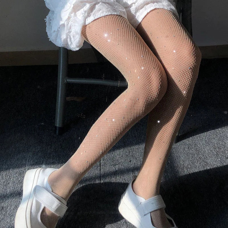 Legs wearing white fishnet stockings and white platform sandals.