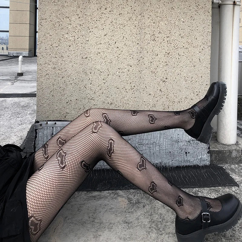 Pair of legs wearing patterned fishnet stockings and black platform shoes.